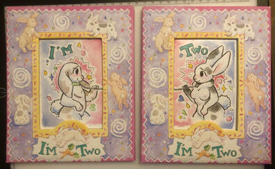 Two of Them A set of two watercolors in soft pastel with rabbit frames that say I’m Two on them. Two anthro rabbit characters stare lovingly from between/across the frames. The rabbits appear to have a chain connecting their collars but are both tenderly touching it,